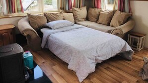 A cozy room with a sofa bed, a small table, and a heater. - Midden Manor Country Stay on a Working Dairy Farm (Ballymena)