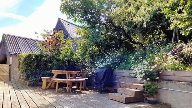 A wooden deck with a picnic table and steps leading to a garden area with various plants and flowers. - Midden Manor Country Stay on a Working Dairy Farm (Ballymena)