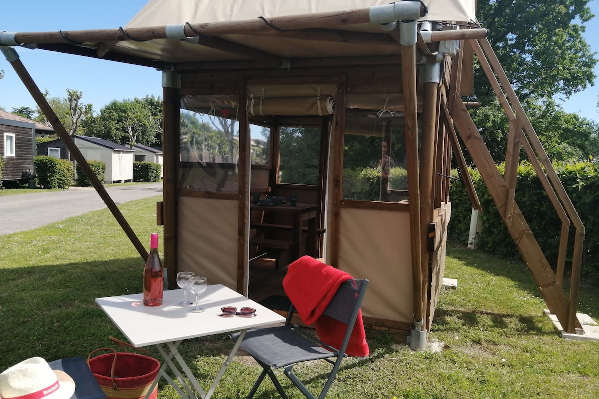 A rustic outdoor seating area with a table, chairs, and a picnic setup.