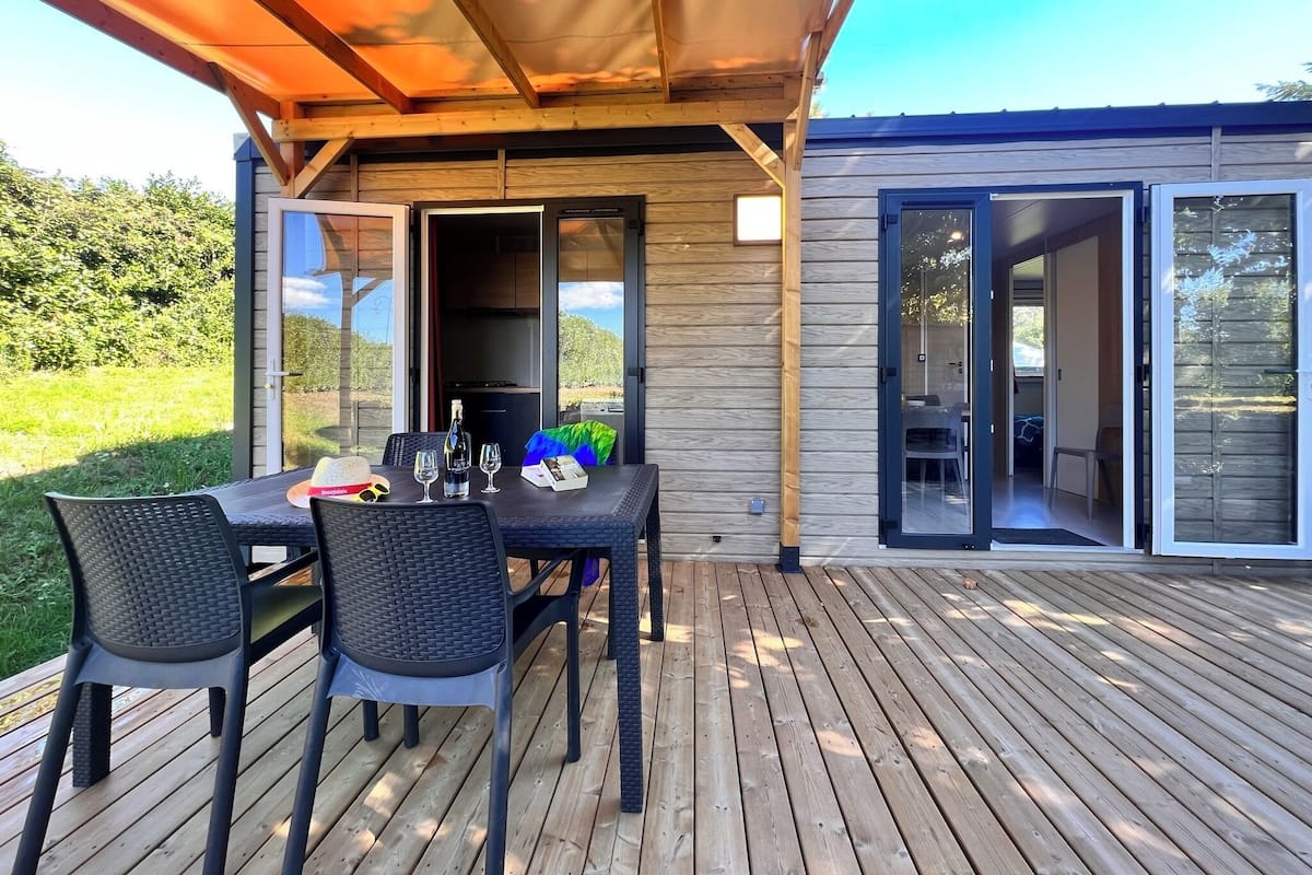 An outdoor patio with a table set for two, a bottle of wine, and a menu.