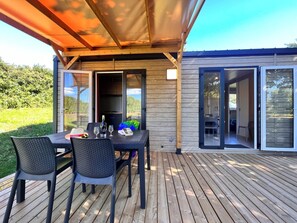 Une terrasse extérieure avec une table dressée pour deux personnes, une bouteille de vin et un menu.