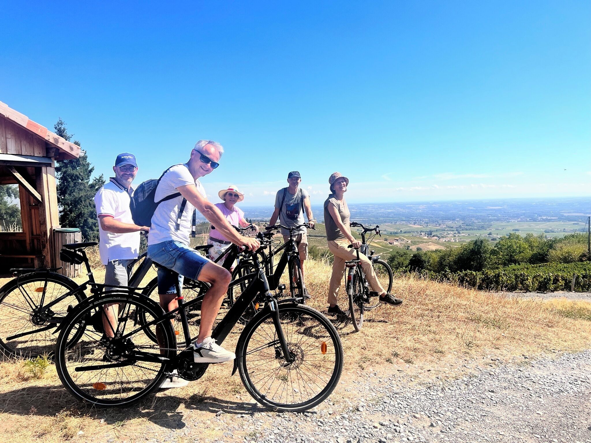 Eine Gruppe von Radfahrern mit einem schönen Blick auf ein Tal und einer Holzhütte im Hintergrund.