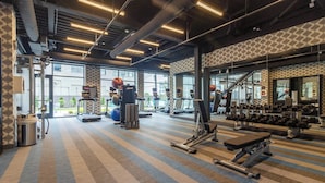 A gym with exercise equipment, a patterned carpet, and large windows.