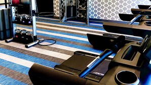 A gym with exercise equipment, a mirrored wall, and a patterned carpet.