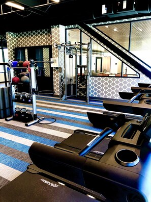 A gym with exercise equipment, a mirrored wall, and a patterned carpet. - Aloft by Marriott St Louis Central West End (St. Louis)