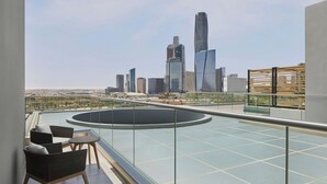 Un balcón con vista a la ciudad, con edificios modernos y una zona de estar circular.