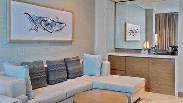 A modern living room with a sofa, a coffee table, and a large mirror reflecting the room.