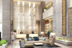 A modern lobby with a reception desk, seating area, and a vertical wooden feature.