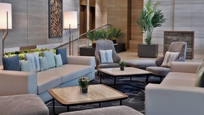 Un vestíbulo moderno con un sofá, sillones, una mesa de centro y una escalera.