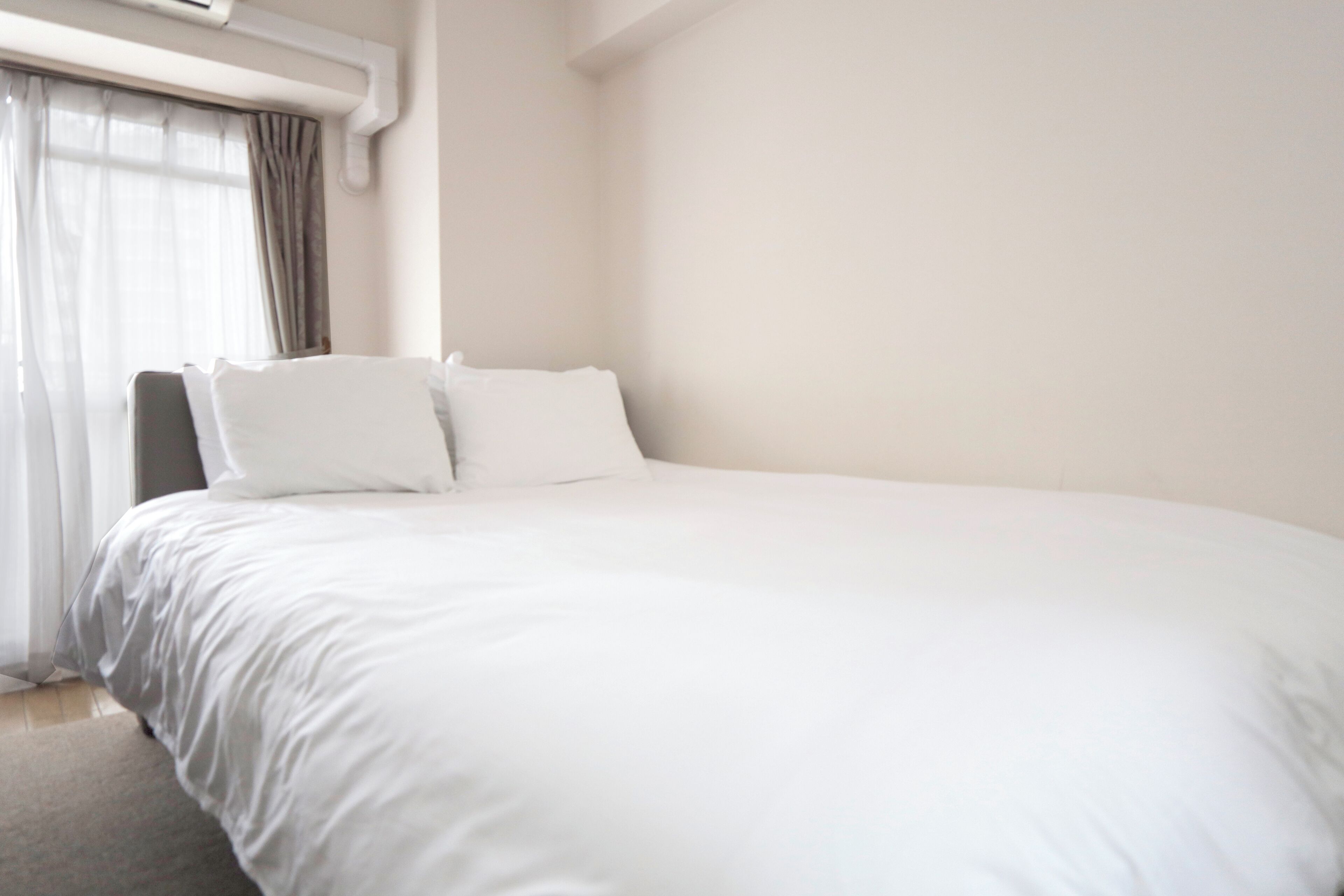 A large bed with white bedding, a headboard, and two pillows.