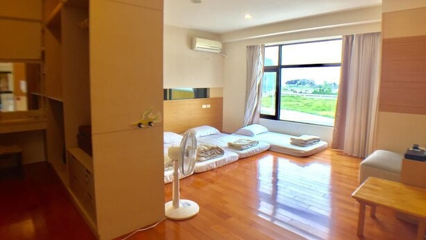 A modern hotel room with a large window, a fan, and a wooden floor. - Penghu Happy Fish (Magong)