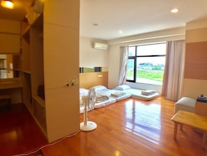 Une chambre d’hôtel moderne dotée d’une grande fenêtre, d’un ventilateur et d’un plancher en bois.