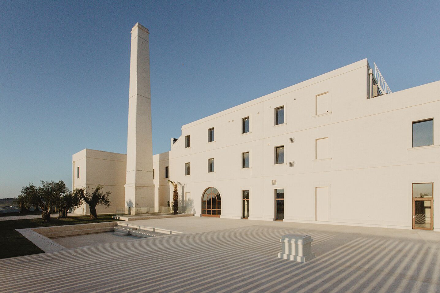 A modern building with a tall central tower, multiple windows, and a covered entrance.