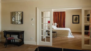 Een kamer met een bed, een bureau en een stoel. Er is een deur die naar een andere kamer leidt.