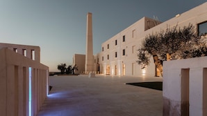 Een ruime binnenplaats met een hoge centrale toren, omgeven door moderne gebouwen met grote ramen en een goed verlicht pad.