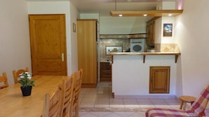 A compact kitchen with a dining area, a sofa, and a small stool. - Ski-in/Ski-out Apartment, 2-Bedroom, Sleeps 6 with South Balcony and Parking (Arêches-Beaufort)