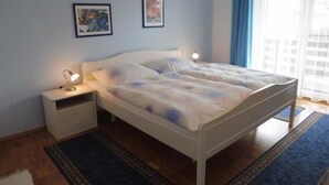 A bedroom with a bed, nightstands, and two framed pictures on the wall.