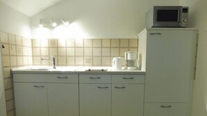 Eine kleine Küchenzeile mit Mikrowelle, Kaffeemaschine und Spüle.