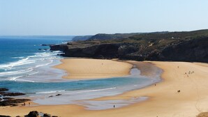 Una playa costera con arena, afloramientos rocosos y una vista despejada del océano.