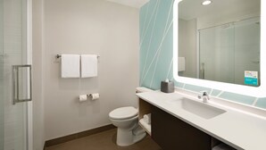 A modern bathroom with a glass shower enclosure, a white toilet, a sink with a mirror, and a towel rack.