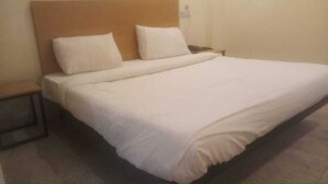 Een standaard hotelkamer met een enkel bed, een nachtkastje en een stopcontact.