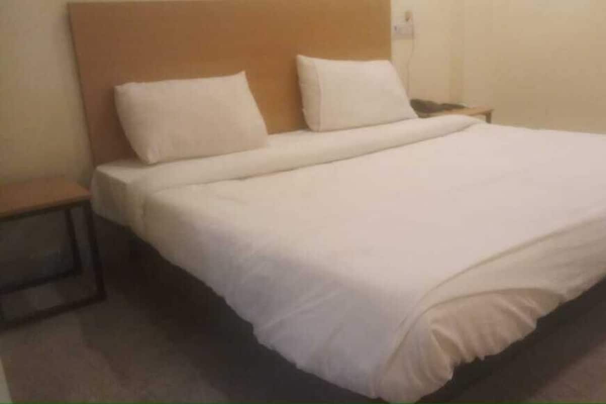 A standard hotel room with a single bed, a nightstand, and a wall socket.