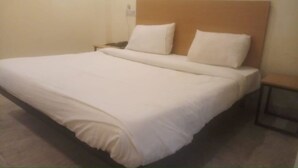 Een net opgemaakt bed met witte lakens in een hotelkamer.