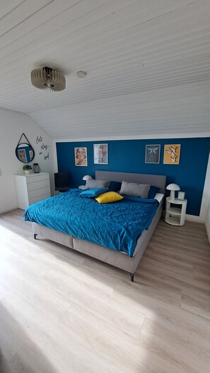 Une chambre à coucher comprenant un lit, des tables de chevet, une commode et des œuvres d’art accrochées aux murs.