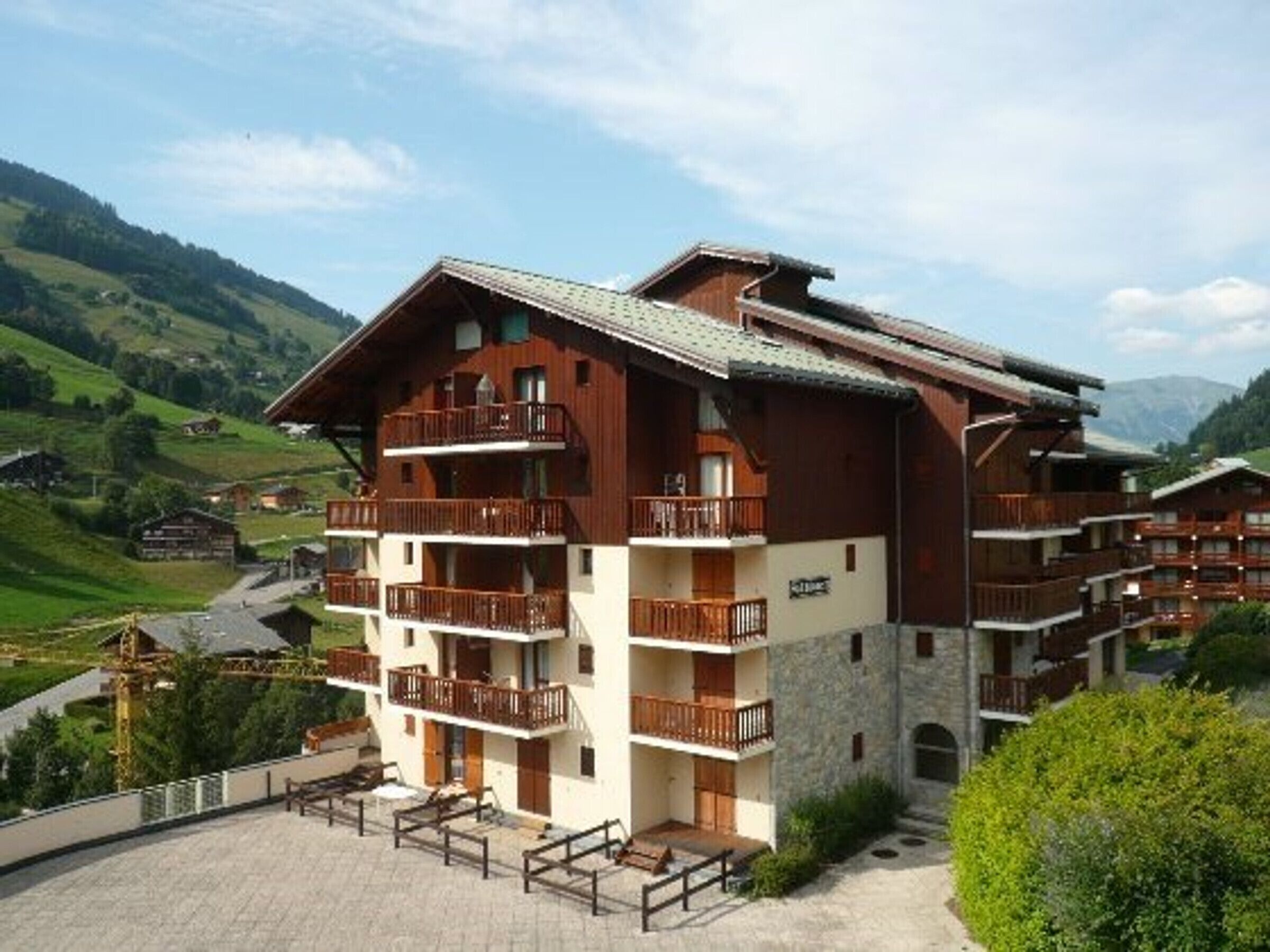 A multi-story hotel with balconies, set in a mountainous area.