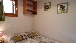 A bedroom with a bed, a wooden shelf, and two framed pictures on the wall. - Apartment for 5 with pool, balcony, close to ski and village (Arêches-Beaufort)