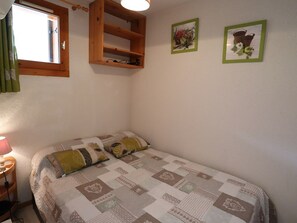 A bedroom with a bed, a wooden shelf, and two framed pictures on the wall. - Apartment for 5 with pool, balcony, close to ski and village (Arêches-Beaufort)