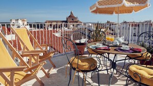 Una terraza con mesas al aire libre, una mesa dispuesta para dos personas y vistas a edificios en el fondo.