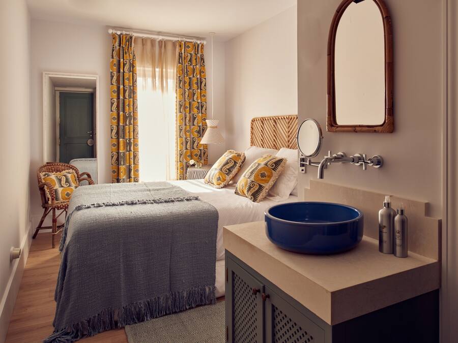 Un dormitorio con cama, un lavamanos azul, un espejo y una puerta.