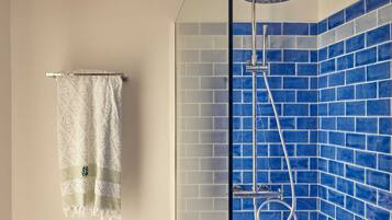 Un baño con ducha, toallero y paredes con azulejos azules.