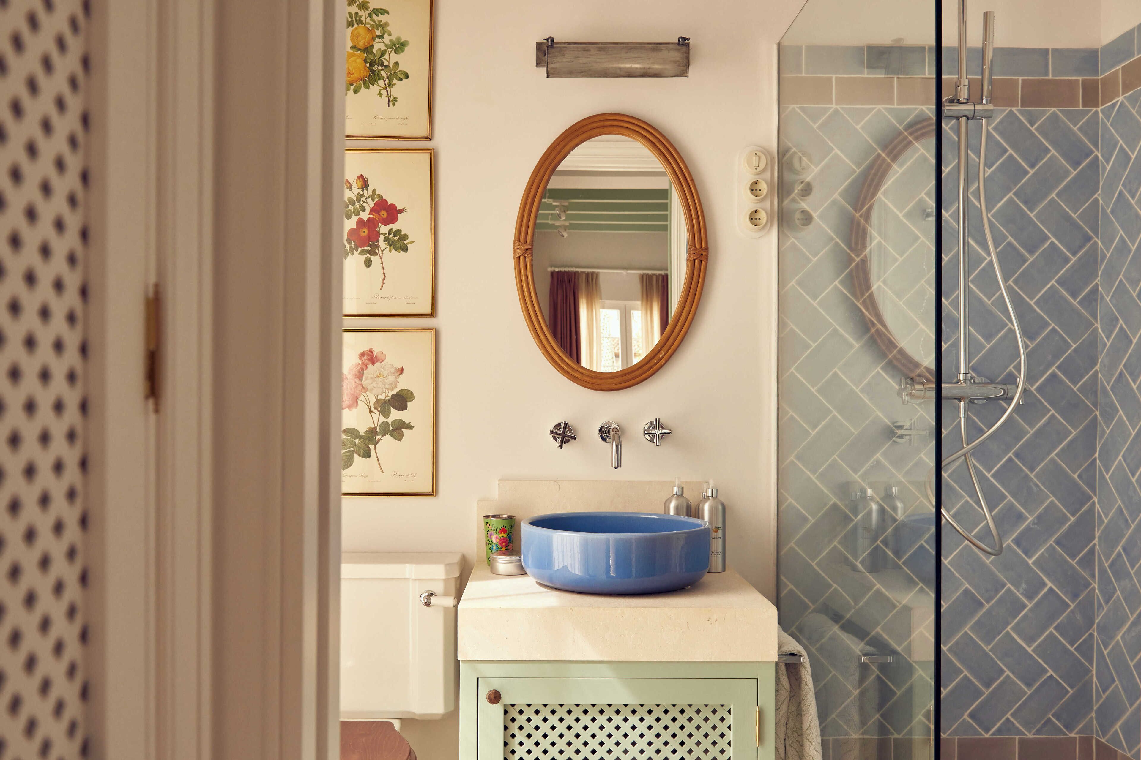 A bathroom with a blue sink, a mirror, and a glass shower enclosure.