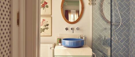 A bathroom with a blue sink, a mirror, and a glass shower enclosure.