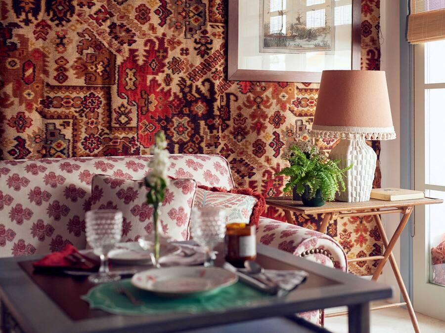 Un rincón comedor acogedor con una pared decorativa, un sofá, una mesa servida con platos, vasos y un jarrón.
