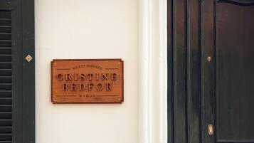 Una placa de madera en una pared que dice 'Guest Houses Cristine Bedfor Mahon'.