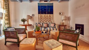 Una sala de estar acogedora con un sofá, dos sillones de ratán, una mesita de centro y una chimenea.
