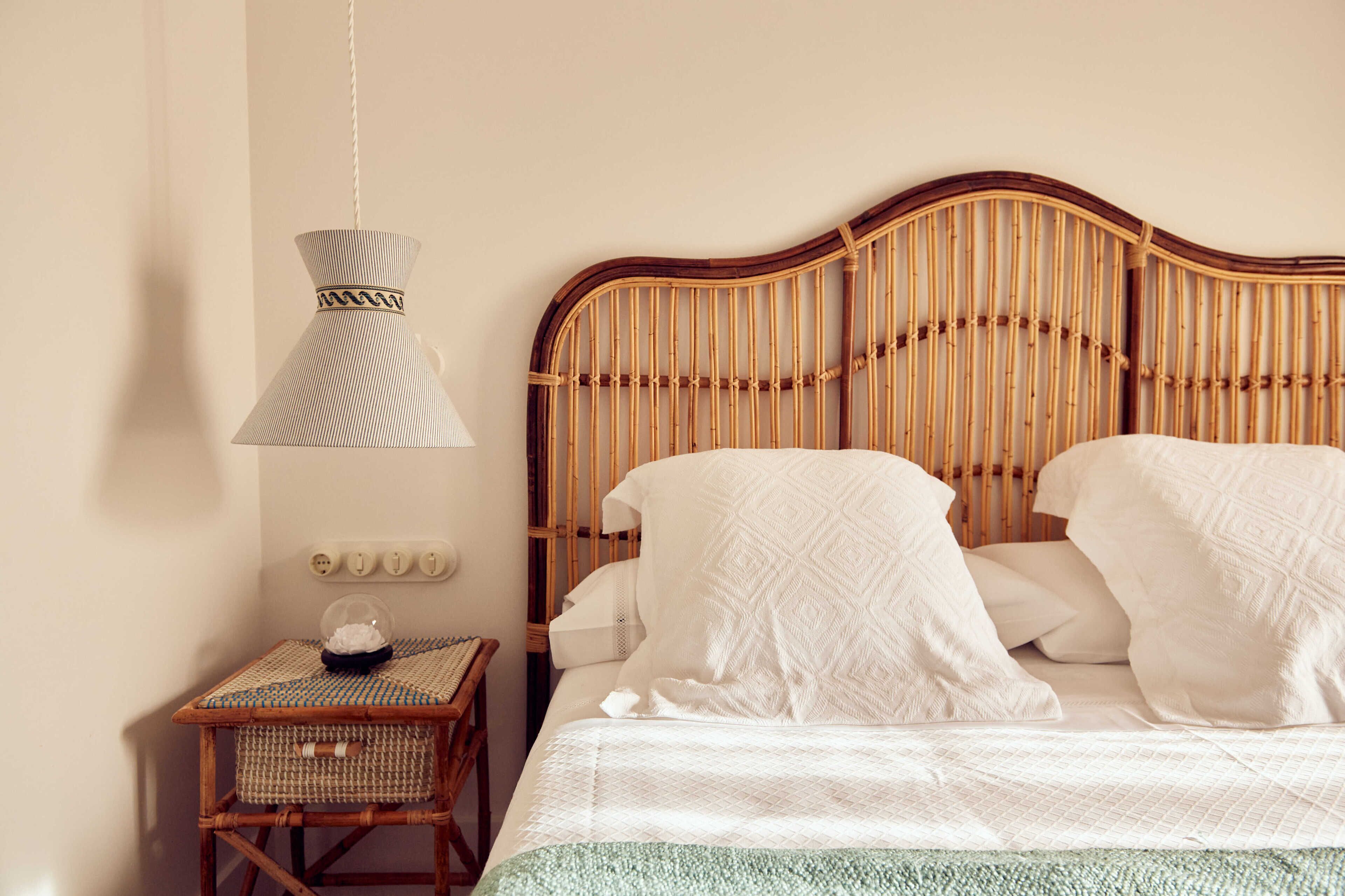 A bed with a woven headboard, a bedside table with a lamp, and a small basket.