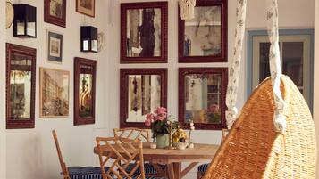 Un comedor con una mesa de madera, sillas de mimbre y varias imágenes enmarcadas en la pared.