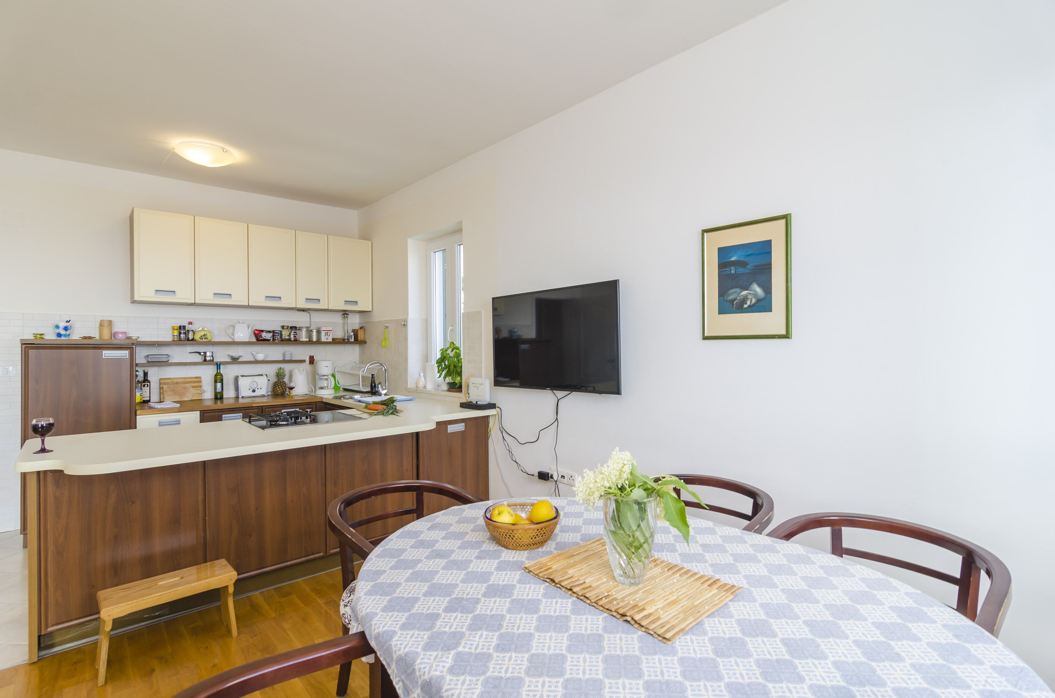 A modern kitchen with wooden cabinets, a built-in island, and a dining area with a table and chairs.
