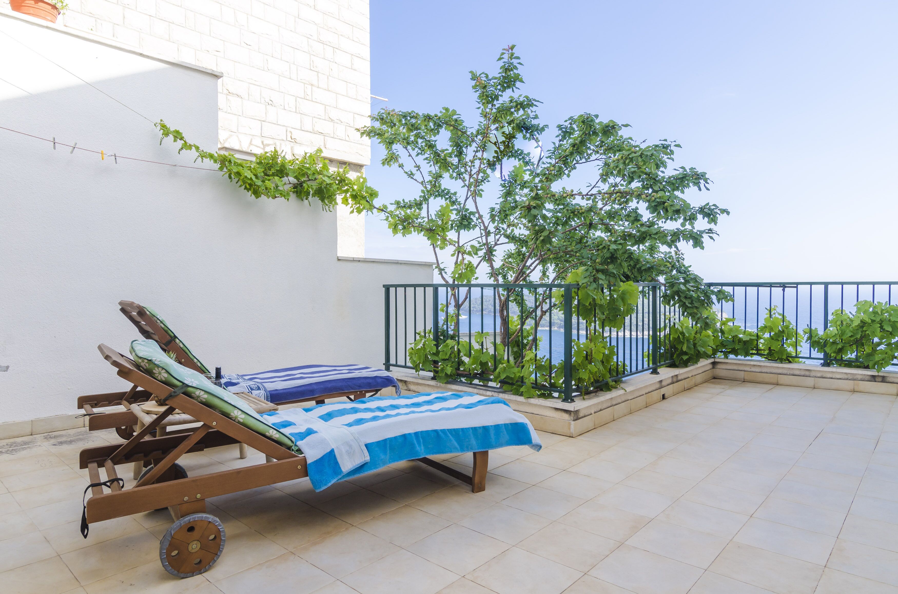 Ein Balkon mit zwei Liegestühlen, gefliestem Boden und Meerblick.
