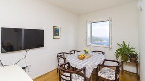 A dining area with a table, chairs, a TV, and a window with a view.