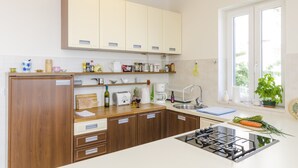 A modern kitchen with wooden cabinets, a gas stove, and a window with a view of greenery.