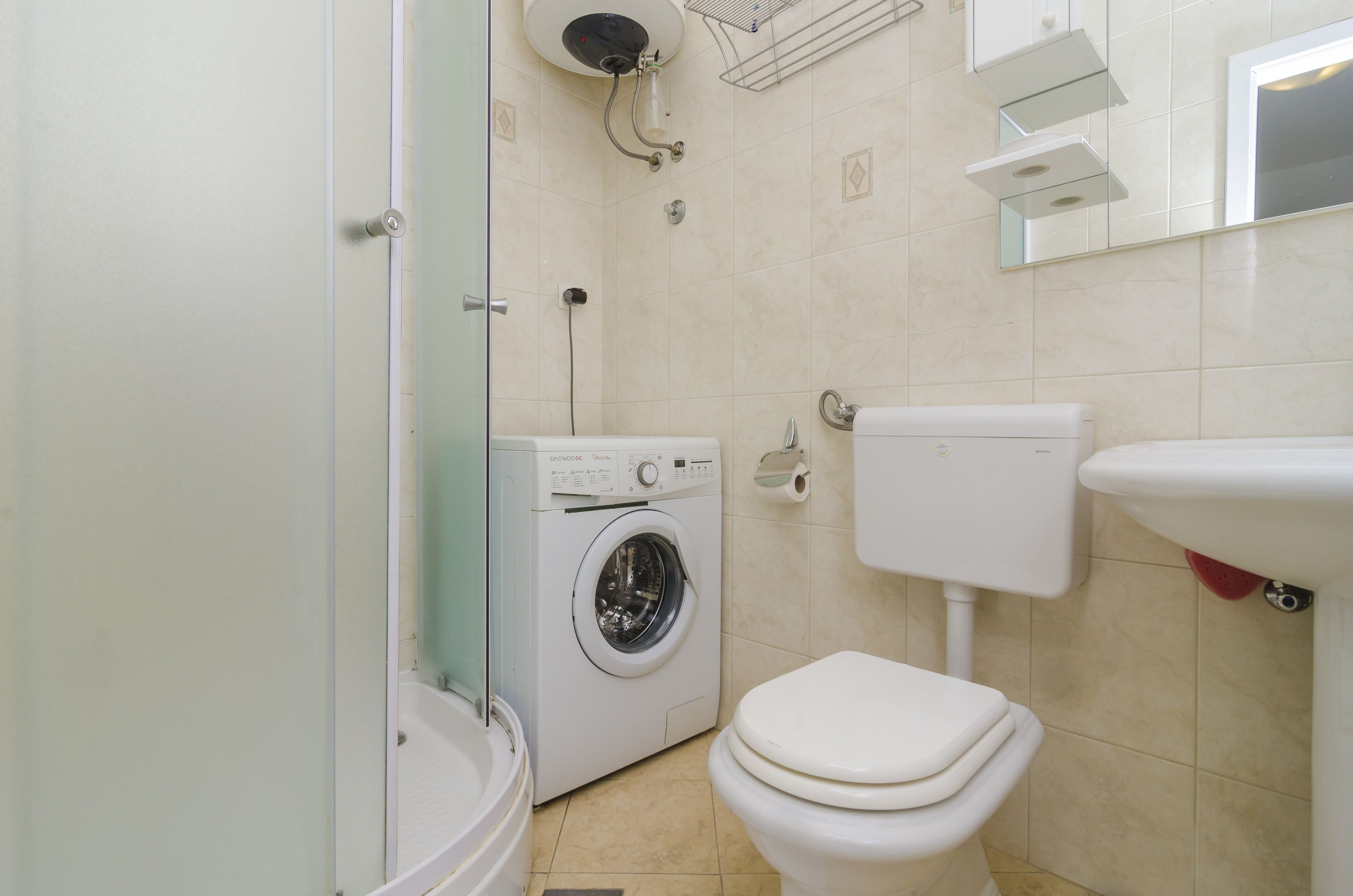 Un baño pequeño con lavadora, inodoro y lavamanos.