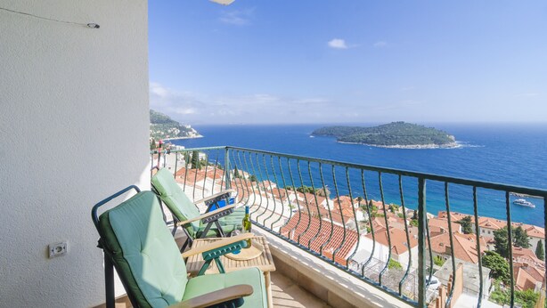 A balcony with a view of the sea and a small island.