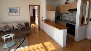 A modern apartment with a living area, kitchen, and a small dining space. - Apartment for up to 4 people, 40 sqm (Prien am Chiemsee)
