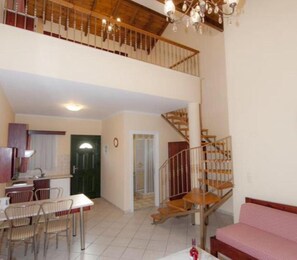 A spacious living area with a staircase, a dining table, and chairs. - Room-l'eremo Luxury Messonete (Corfu)