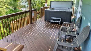 Une terrasse en bois avec un jacuzzi, une table et deux chaises.